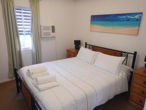 a bedroom with a large white bed with towels on it at Pine Cottage in Brisbane