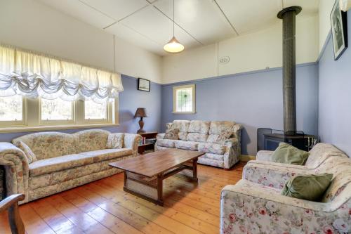 a living room with two couches and a table at Beacon Cottage - Cosy Family Retreat in Lake Tyers