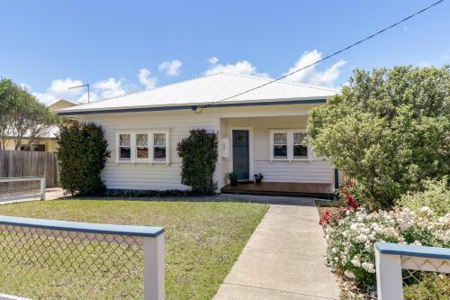 a white house with a fence in front of it at Beacon Cottage - Cosy Family Retreat in Lake Tyers