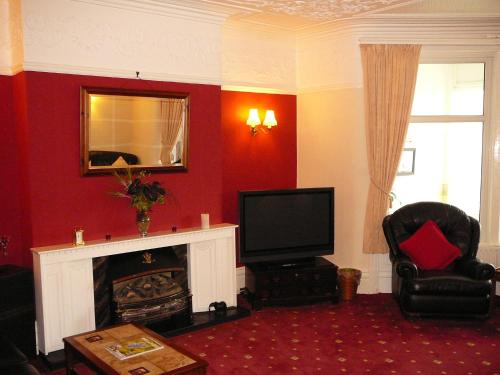 ein Wohnzimmer mit einem Kamin und einem TV in der Unterkunft The Craigmore in Blackpool