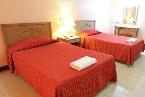 Habitación de hotel con 2 camas con sábanas rojas en Pin Hotel en Lampang