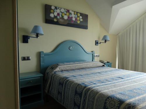 a bedroom with a bed with a blue head board at Hotel Los Juncos in Noja