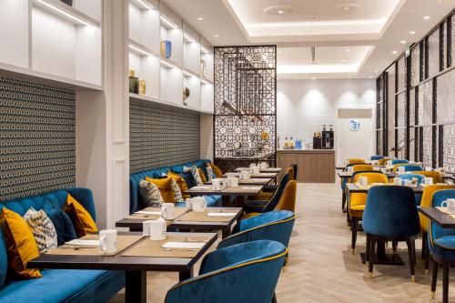 a dining room with tables and blue chairs at Eurostars Puerta Real in Granada