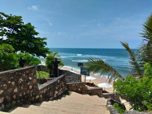 um caminho que leva a uma praia com o oceano em Balangan Paradise Hostel and Restaurant em Jimbaran