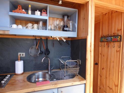 a kitchen with a sink and a shelf with utensils at Dune & Domes Pichilemu in Pichilemu