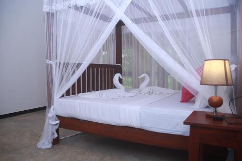 a bedroom with a canopy bed with swans on it at Villa Greenary in Unawatuna