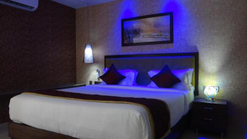 a bedroom with a large bed with purple lighting at Arna Hotel in Devanahalli-Bangalore