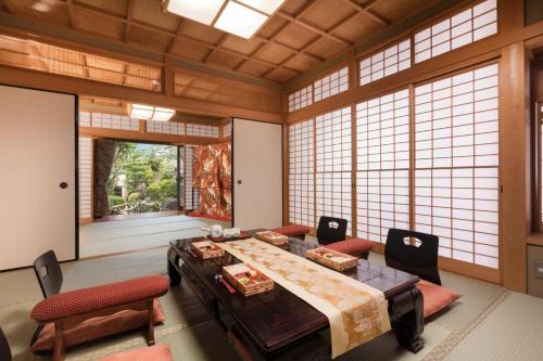 a large room with a table and chairs and windows at Kyo-machiya Stay WAKA Fushimiinari in Kyoto