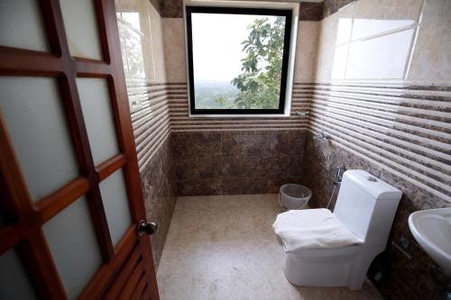 a bathroom with a window and a toilet and a sink at Hill House Waves and Shores in Kottayam