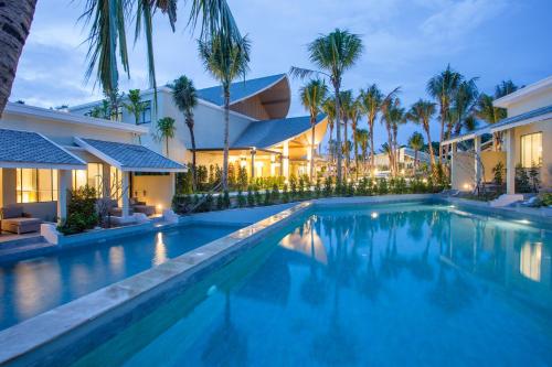 a swimming pool in front of a house with palm trees at CRAFT Resort & Villas, Phuket Town - scheduled shuttle to Phuket Old Town in Phuket