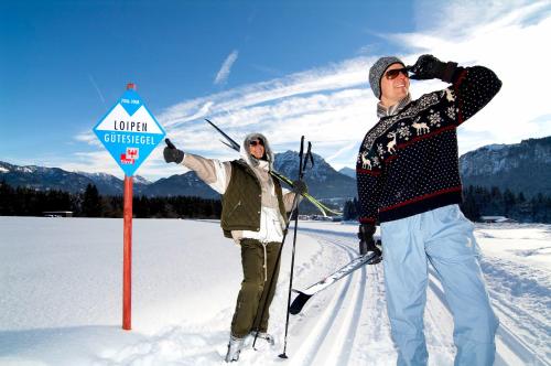 a man and woman standing next to a sign in the snow at Alpenmotel Säuling in Reutte