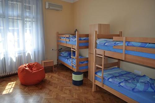 um quarto com três beliches e uma janela em Habitat Hostel em Belgrado