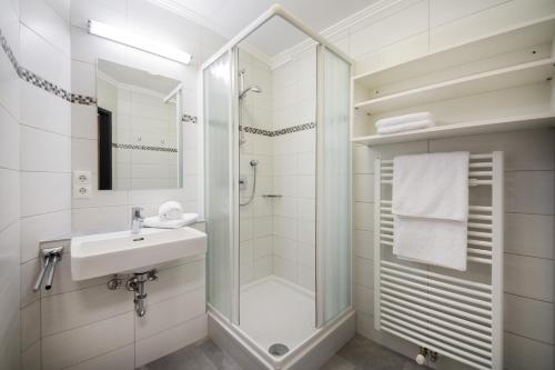 a white bathroom with a sink and a shower at Knappensteig Appartements in Wagrain
