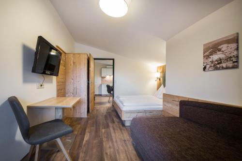 a room with a bed and a desk and a television at Knappensteig Appartements in Wagrain