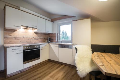 a kitchen with white cabinets and a wooden table at Knappensteig Appartements in Wagrain
