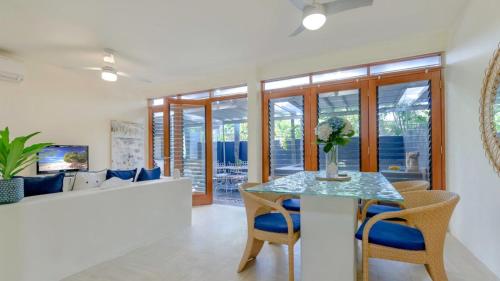 a dining room with a table and chairs and a couch at Beachside 3 with Private heated plunge pool in Port Douglas