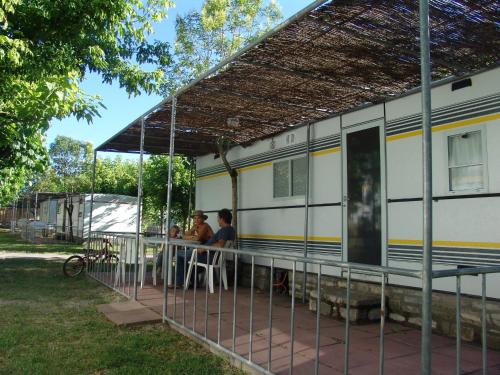 two people sitting at a table outside of a train car at Bungalows Peña Montañesa in Aínsa