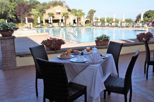 een tafel en stoelen met een tafel en een zwembad bij OasiMaremma Village in Scarlino