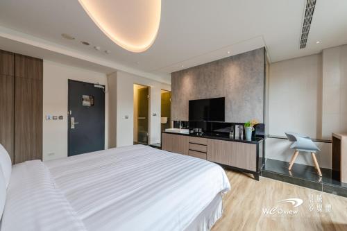 a bedroom with a white bed and a flat screen tv at Wow Happy- Taipei in Taipei
