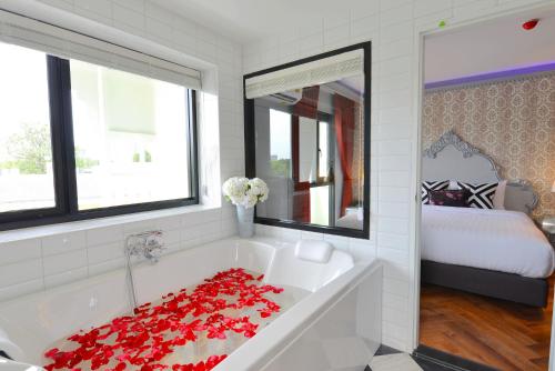 a white bathroom with a tub with red roses on it at Villa De Khaosan by Chillax - SHA Extra Plus in Bangkok