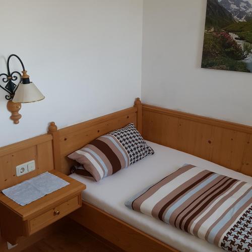 a bed with a wooden headboard and a night stand at Lenggrieser Hof in Lenggries