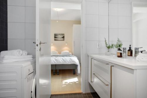 a white bathroom with a bed in the background at BJØRVIKA APARTMENTS, Opera Area, Oslo city center in Oslo