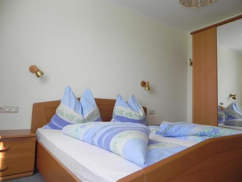 a bedroom with a bed with blue pillows on it at Apartments Kleinseeblick in Sankt Kanzian