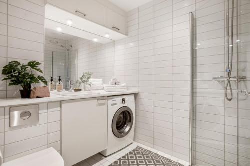 a white bathroom with a washing machine and a shower at BJØRVIKA APARTMENTS, Opera Area, Oslo city center in Oslo