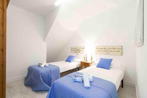 2 camas en una habitación de color azul y blanco en The Rentals Collection | Coeur, en San Sebastián