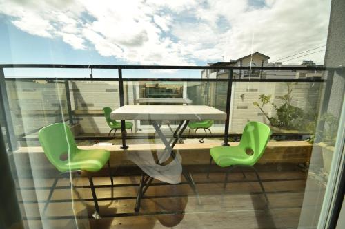 a balcony with a table and green chairs at Walk in the Wind Homestay in Taitung City