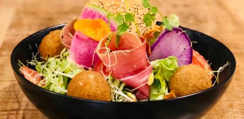 a black bowl filled with a salad on a table at Le Solan d'Aniathazze in Peisey-Nancroix