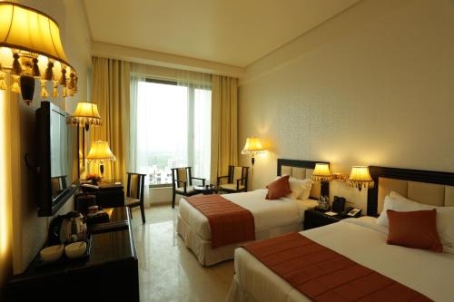 a hotel room with two beds and a television at Royal Tulip Navi Mumbai in Navi Mumbai