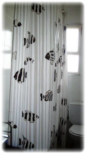 a bathroom with a black and white shower curtain with fish on it at La Masia in Sant Pere Pescador