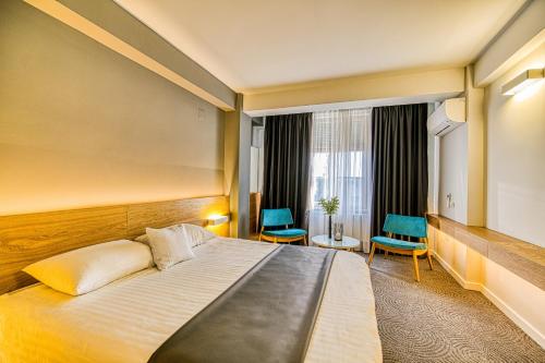 um quarto de hotel com uma cama e duas cadeiras azuis em Hotel Silva em Timişoara