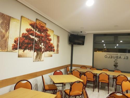 a dining room with tables and chairs and a flat screen tv at Hostal Restaurante El Abuelo in Trobajo del Camino
