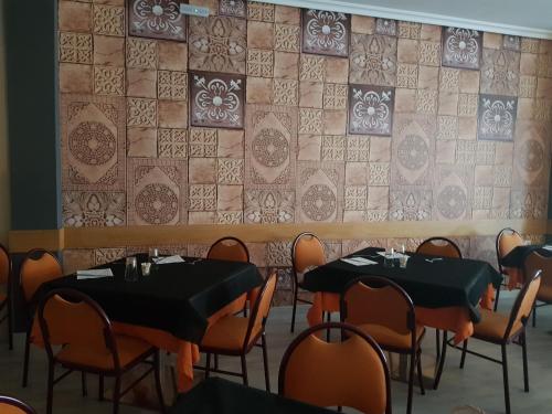 a dining room with tables and chairs and a wall at Hostal Restaurante El Abuelo in Trobajo del Camino