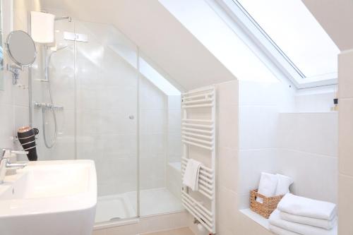 a white bathroom with a shower and a sink at Weisse Düne - Ost in Wenningstedt