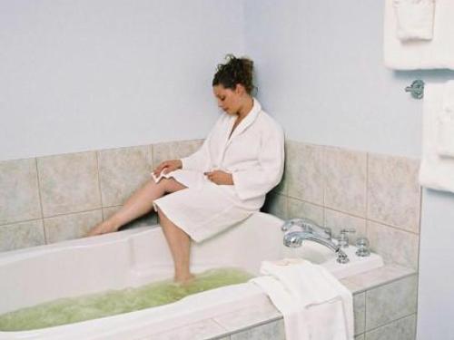 a woman sitting in a bath tub in a bathroom at New Horizon Motel in Christina