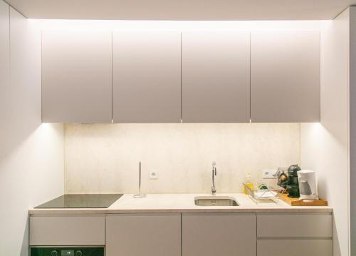 eine Küche mit weißen Schränken und einer Spüle in der Unterkunft Grand Ouro Deluxe Apartment Downtown Baixa in Lissabon