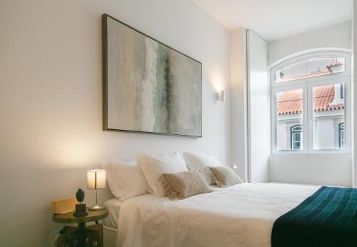 リスボンにあるGrand Ouro Deluxe Apartment Downtown Baixaの白いベッドと壁に絵画が飾られたベッドルーム1室