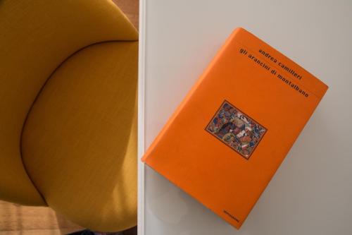 an orange book sitting on top of a chair at Plebis - B&B in Sicilia nel centro storico di Catania in Catania