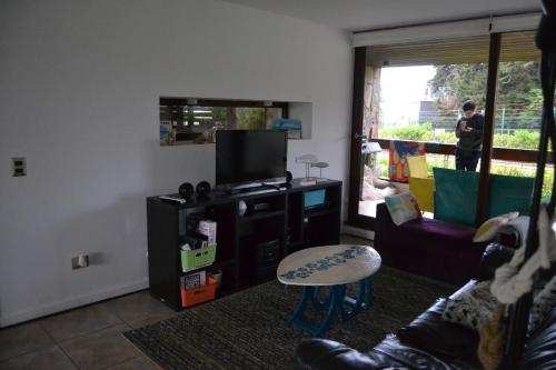 a living room with a couch and a table and a tv at Departamento Maitencillo Costamai in Maitencillo