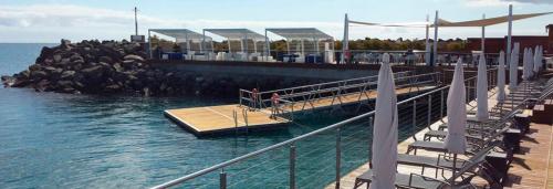 a dock with a person sitting on it in the water at Villas Pasito Blanco in Pasito Blanco