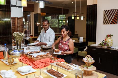 a man and a woman standing behind a table with food at Calypso Hôtel in Toamasina