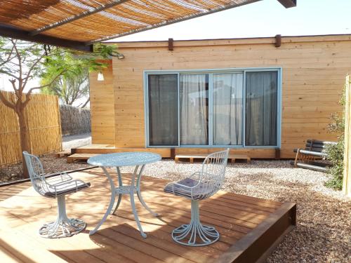un patio con mesa y sillas en una terraza en צימרגולה, en ‘En Yahav