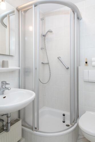 a white bathroom with a shower and a sink at Weisse Düne - App.. 4 in Wenningstedt
