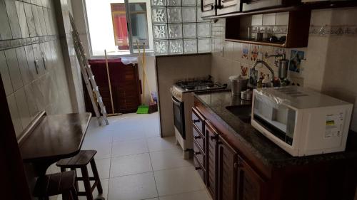 La cocina está equipada con microondas, fregadero y fogones. en Apartamento na Prainha (1 quadra), en Arraial do Cabo