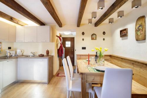 a kitchen with a wooden table and white chairs at HelloChalet - Chalet Grené typical house with garden - 1km cabelcar in Valtournenche