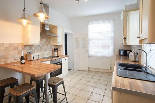 uma cozinha com armários brancos e um balcão de madeira em Host & Stay - Windsor Cottage em Saltburn-by-the-Sea