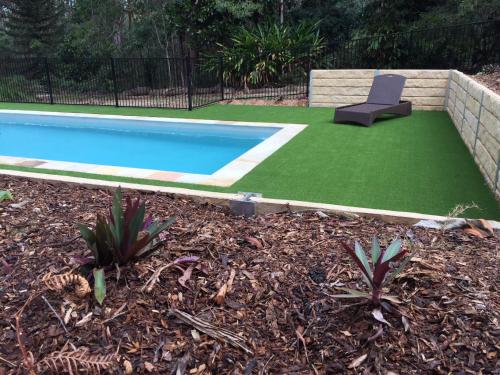 a pool with a chair in a yard with grass at Eatons Retreat in Eatons Hill